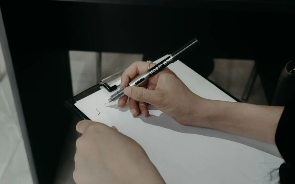 Hands filling in compliance paperwork on a clipboard, recording WEEE disposal documentation