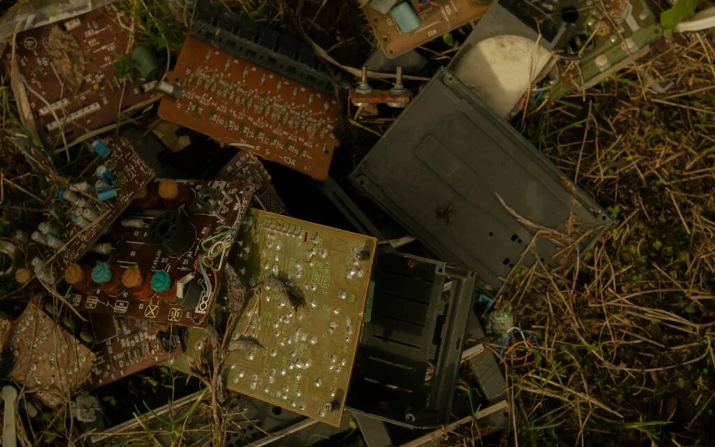 Pile of old, broken electronics dumped outdoors, an example of e-waste