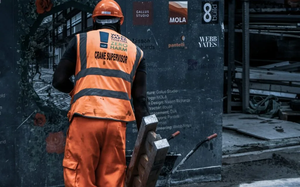 Recycling worker in an orange safety vest handling recovered metal at a certified treatment facility